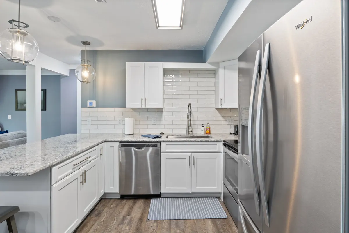 A sleek kitchen scene highlighting granite countertops, modern stainless steel appliances, and elegant pendant lighting. The open layout is ideal for preparing meals together or hosting gatherings, reflecting both style and utility.