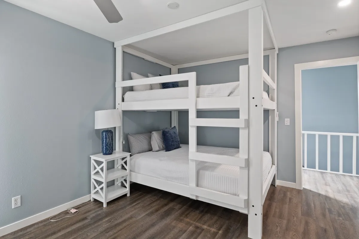 A playful bedroom setup with a sturdy bunk bed dressed in decorative pillows, a cozy nightstand with a lamp for evening reading, and soft touches that suggest a family-friendly, comfortable environment. The space radiates an atmosphere ideal for both restful sleep and cherished memories.