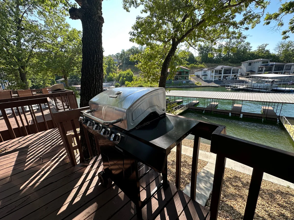 A spacious deck overlooks the water, complete with a grill and surrounded by lush trees. The inviting setup encourages outdoor relaxation, gatherings, and provides ample space for pets to enjoy the fresh air. The calming water view and casual furnishings reinforce the property’s focus on comfort and outdoor living.