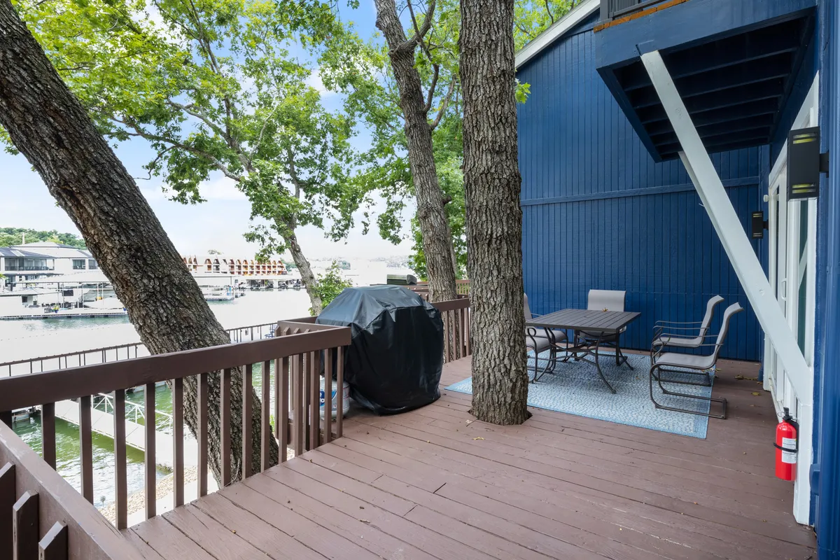 An inviting outdoor dining set with a grill is set against a backdrop of trees and a beautiful water view, capturing the essence of outdoor dining and socializing by the waterfront.