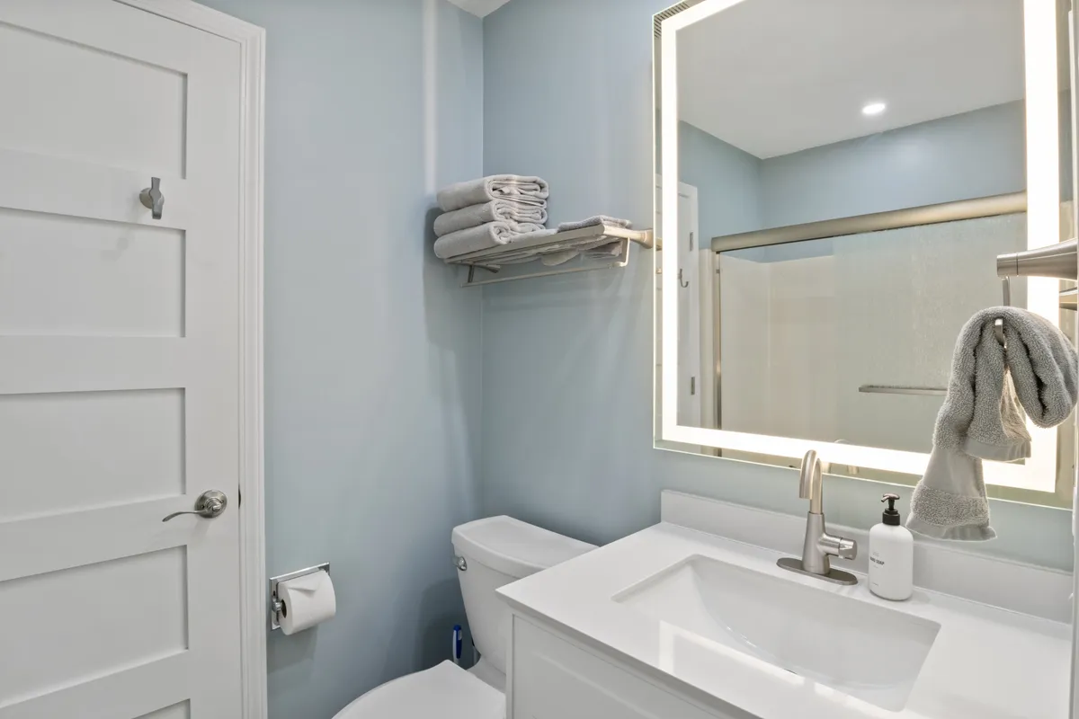 A modern, sparkling clean bathroom with a contemporary sink, large mirror, fresh towels neatly stacked, and a spacious shower area. The overall ambiance is calm and inviting, with practical features ideal for daily self-care routines and relaxation.